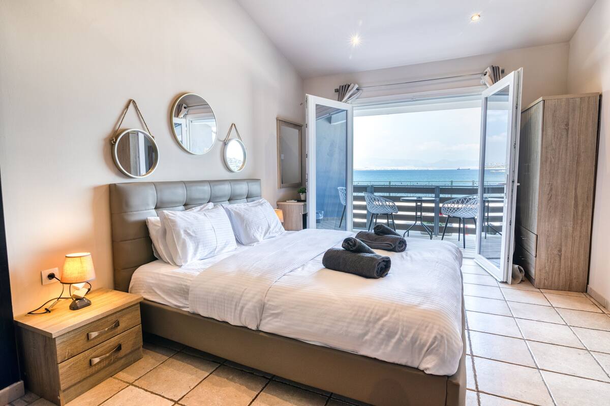 A bedroom with a bed, bedside table, and a view of the balcony.
