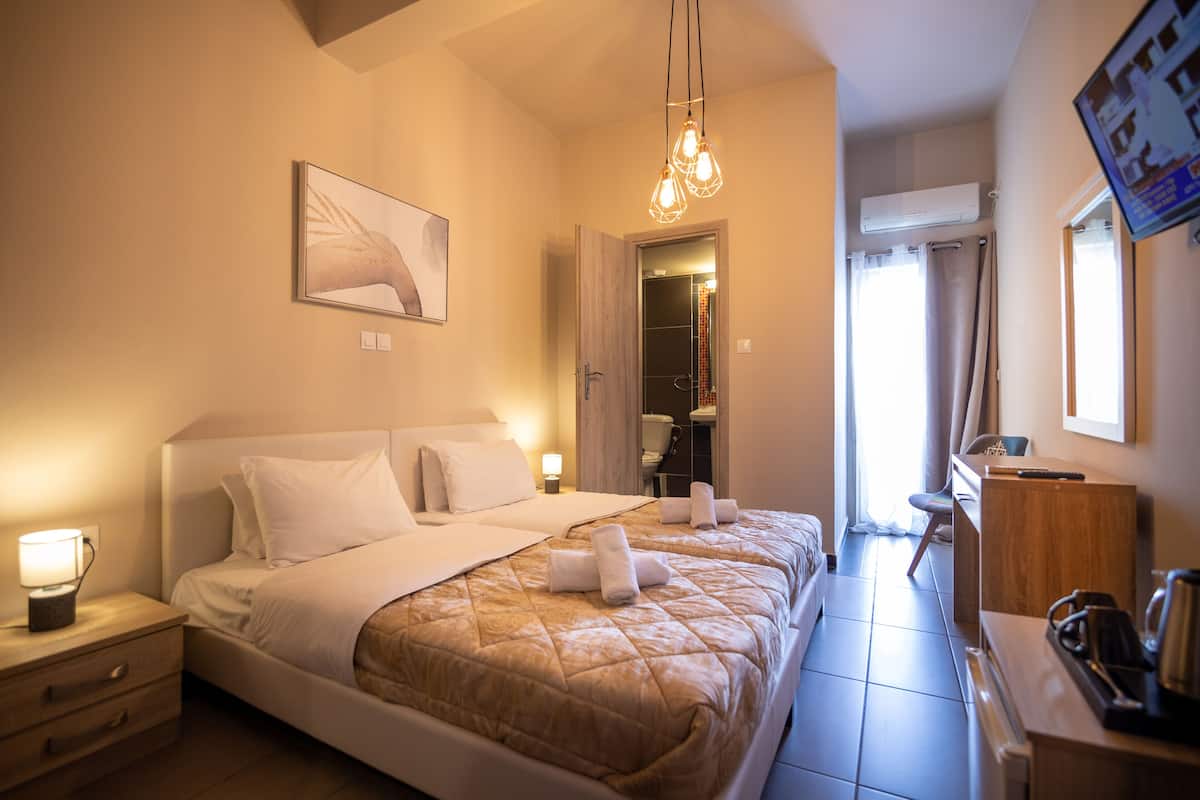 A hotel room with a large bed, bedside lamps, a desk with a chair, and a flat-screen TV mounted on the wall.