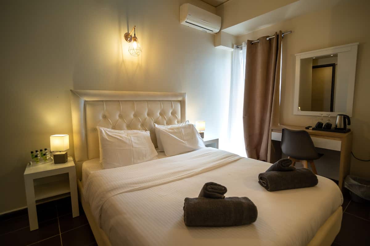 A neatly made bed with pillows, a bedside lamp, and two rolled towels.