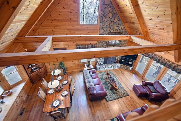 Ein großzügiger Loft-Raum mit hohen Decken, Holzbalken, einem Kamin aus Stein, einem Essbereich und einer gemütlichen Sitzecke.