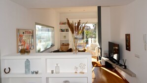 A modern living room with a large window, a TV, and a bookshelf. - VILLA PONENT (L'Escala)