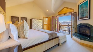 Une chambre avec un grand lit, une cheminée et un balcon offrant une vue dégagée.