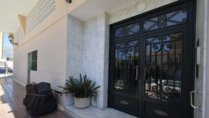 A building entrance with a black metal gate, a potted plant, and a covered object on the ground. - MARISCAL 6 (1 BEDROOM) (Benidorm)
