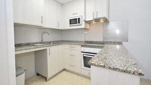 A kitchen with white cabinets, a granite countertop, a built-in microwave, a stainless steel range hood, and a dishwasher. - MARISCAL 6 (1 BEDROOM) (Benidorm)