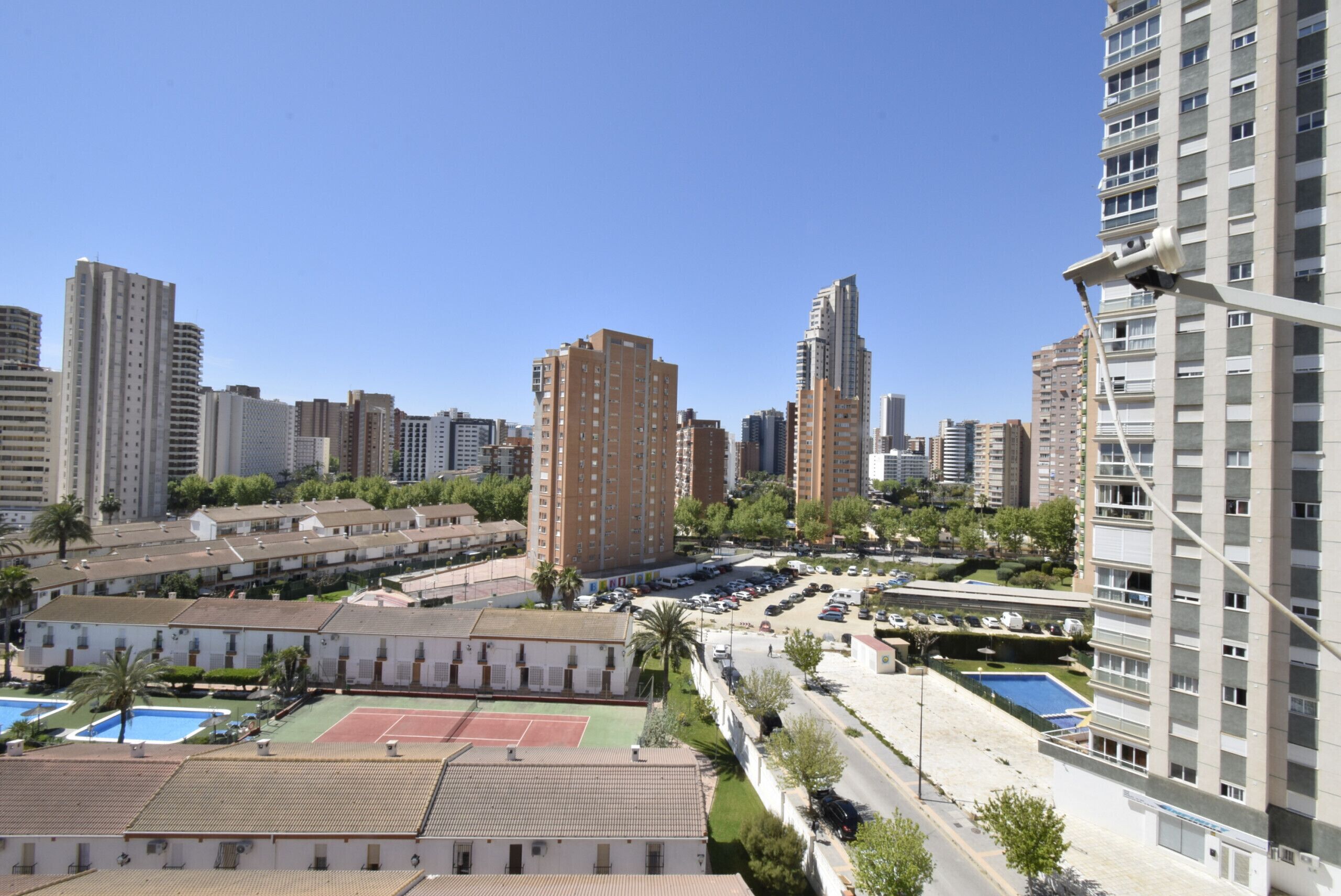 A residential area with high-rise buildings, a tennis court, and a swimming pool.