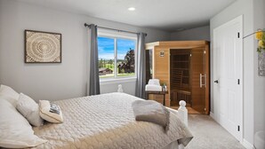 A bedroom with a bed, a window with curtains, a door, and a view of the outdoors. - Majestic Mountain Views! (Kalispell)