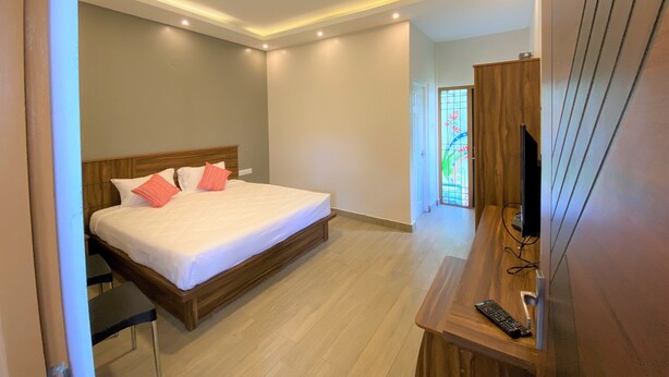 A modern bedroom with a wooden bed, a desk with a TV, and a stained glass window. - AVALON STAYS  OOTY (Ootacamund)