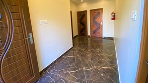 A hallway with marble flooring, wooden doors, and a fire extinguisher. - AVALON STAYS  OOTY (Ootacamund)