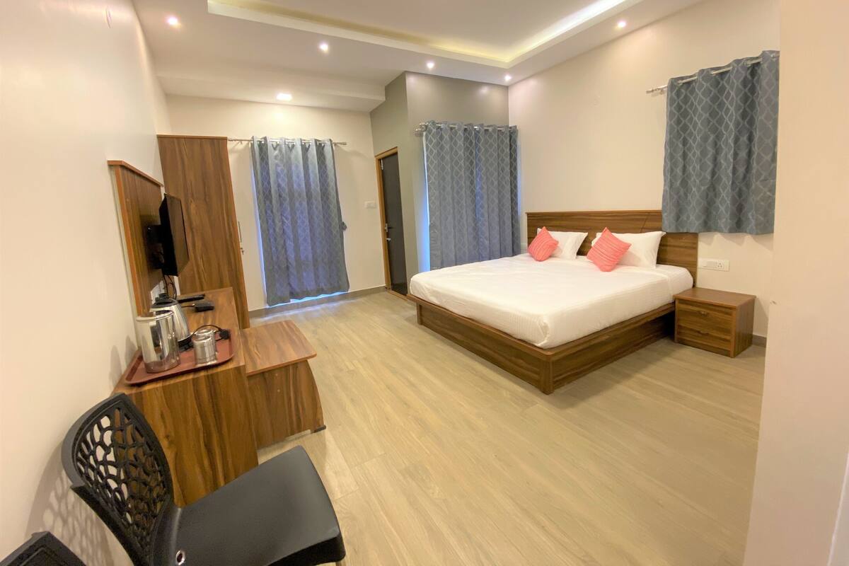 Una habitación de hotel con cama, mesita de noche, escritorio, silla y televisión.