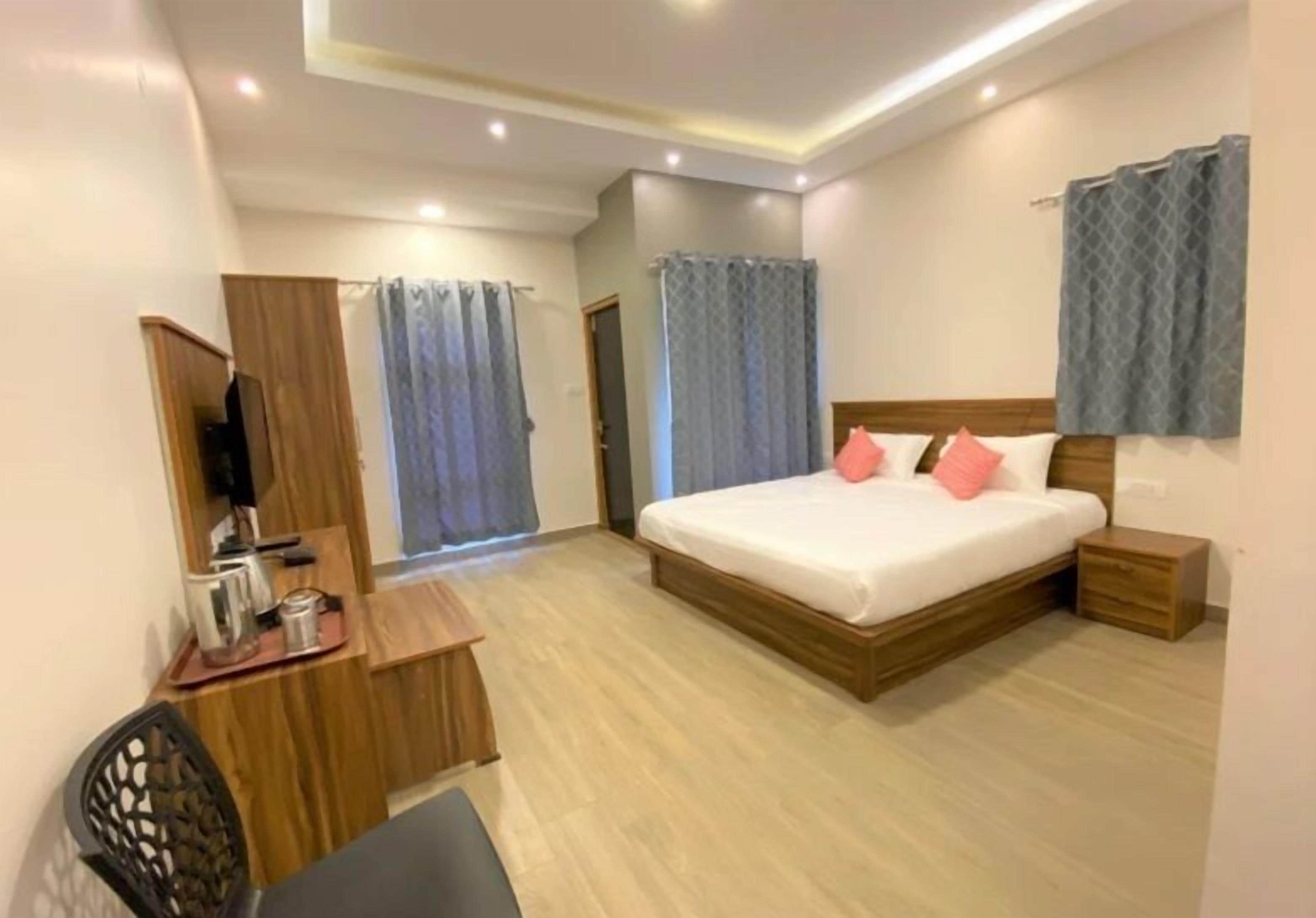 A hotel room with a bed, bedside table, desk, chair, and a television.
