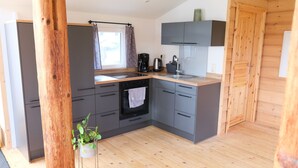 Eine moderne Küche mit grauen Schränken, Holzboden und einem eingebauten Ofen.