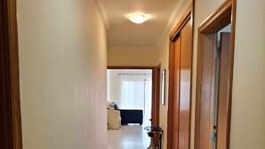 Ein Flur mit gefliestem Boden, Holztüren und einer Deckenleuchte.
