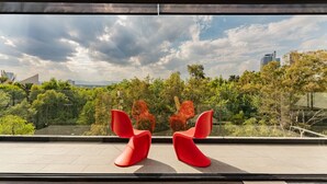 Ein modernes Interieur mit einem großen Fenster mit Blick auf eine Stadtlandschaft und üppiges Grün.