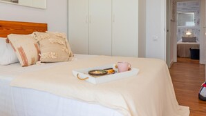 A neatly made bed with a tray of breakfast items, a pink mug, and a wooden headboard. - Cozy Beachfront Apartment in Palamós (Palamós)
