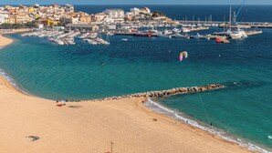 A coastal town with a sandy beach, a marina with boats, and a rocky breakwater. - Cozy Beachfront Apartment in Palamós (Palamós)