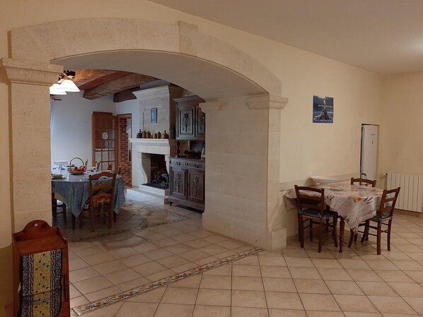 Un comedor con una mesa y sillas, una chimenea y una cocina visible a través de un arco.