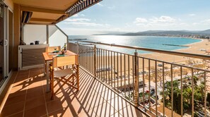 Enjoy the breathtaking view of the beach from this balcony with a table and chairs.