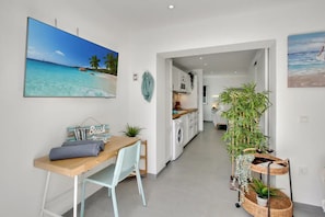 Una cocina moderna con armarios blancos, lavadora y un comedor con mesa y sillas.
