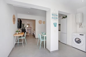 A modern kitchen with a washing machine, a dining area with chairs, and a sign indicating a 'Hip Flop Zone.'