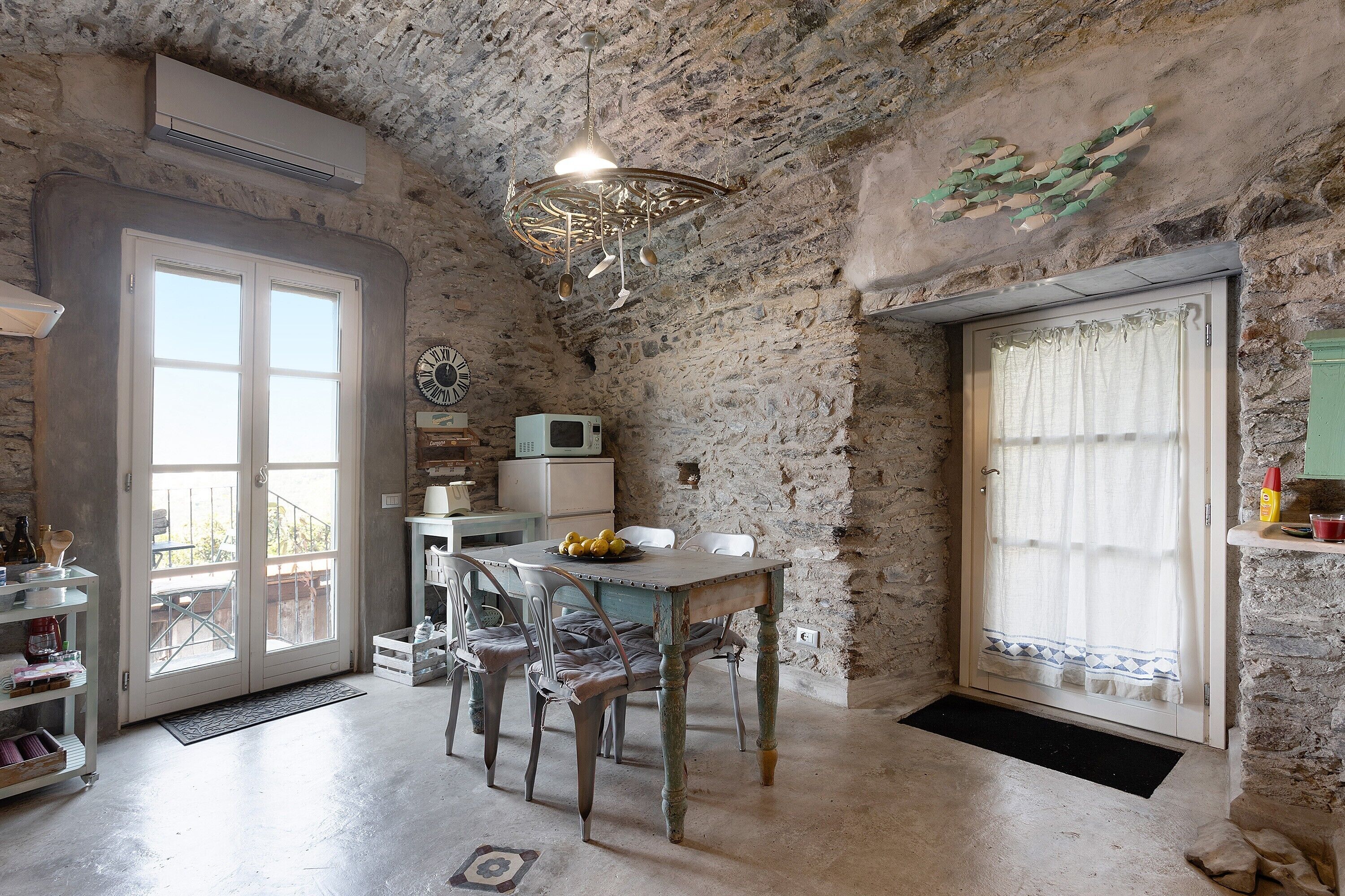 Una cucina rustica con pareti in pietra, un tavolo di legno e un lampadario.