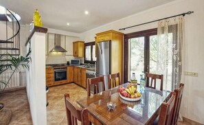 Een moderne keuken met houten kastjes, een roestvrijstalen koelkast en een eettafel gedekt met fruit.