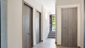 A hallway with wooden doors and a staircase leading to an outdoor area.