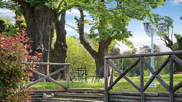 A wooden fence, a bench, and a lamppost in a park setting.