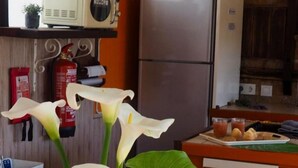 A kitchen with a refrigerator, a microwave, a coffee maker, and a table with a vase of flowers. - Vacation Home 'Las Vistas' with Mountain View, Private Terrace and Wi-Fi (Valleseco)