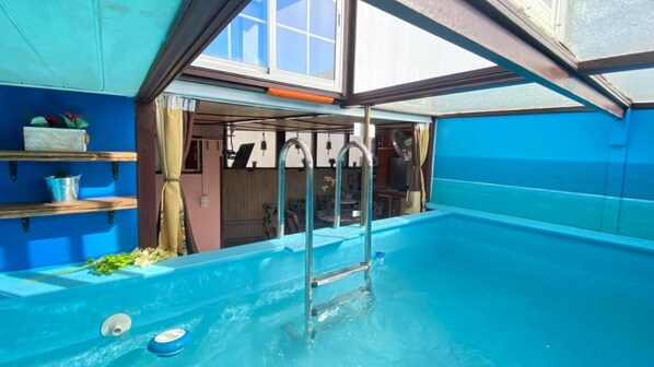 A pool with a ladder, a window, and a shelf with items.