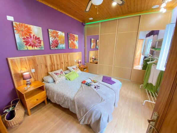 A bedroom with a wooden headboard, a bed with multiple pillows, a nightstand, a lamp, and a mirror.