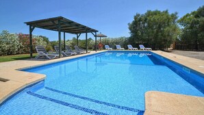 Una piscina con sillas de descanso y un área cubierta.