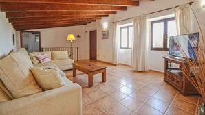 Una sala de estar con un sofá, una mesa de centro, un mueble para televisión y una lámpara.
