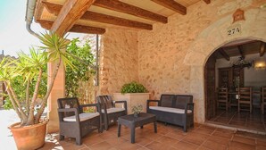 Un patio con mobiliario de mimbre, una planta en maceta y un muro de piedra.