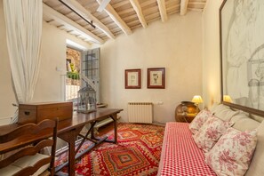 Una habitación con edredón a cuadros, un escritorio de madera, un radiador y dos cuadros en la pared.