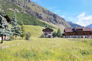A mountain lodge with a wooden exterior, a covered porch, and a view of the surrounding hills.
