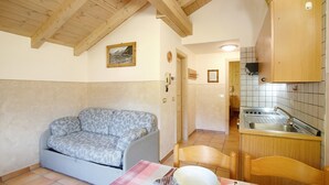 A compact living space with a sofa, dining table, and kitchen area. - Apartment 'Appartamenti Lorenza 3 Baite Giotto' with Mountain View, Shared Garden and Wi-Fi (Livigno)