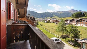 A wooden balcony with a view of a village and mountains. - Apartment 'Appartamenti Lorenza 3 Baite Giotto' with Mountain View, Shared Garden and Wi-Fi (Livigno)