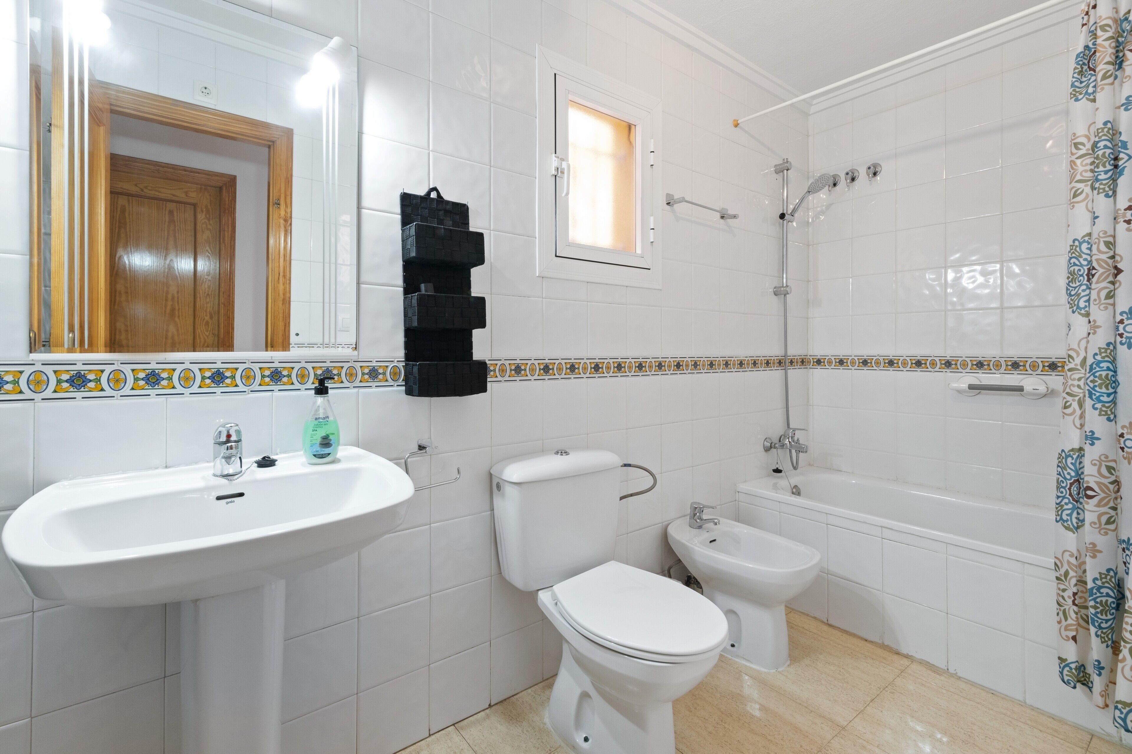 A bathroom with a sink, toilet, bidet, and bathtub.