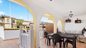 A balcony with a table and chairs, a sofa, and a view of buildings. - Holiday Home 'casa en la playa con piscina y terraza MAX' (Gran Alacant)