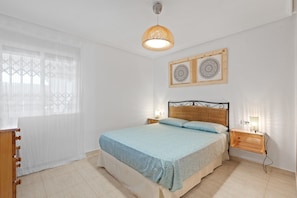 Una camera da letto con un letto, comodini, una lampada a sospensione e decorazioni murali.