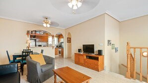 Ein Wohnzimmer mit einer Couch, einem Holztisch, einem Fernseher und einer Treppe.