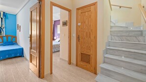 Ein Hotelzimmer mit einem Bett, einer Holztür, einer Treppe und einem Gang, der zu einem weiteren Raum führt.