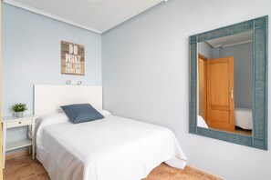 Ein Schlafzimmer mit Bett, Nachttisch, Spiegel und einem motivierenden Zitat an der Wand.