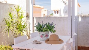 A white table with a woven hat, a potted plant, and a few stones. - Holiday Home 'Casa en la playa con piscinas 11 A' with Shared Pool, Wi-Fi and Air Conditioning (el Gran Alacant)