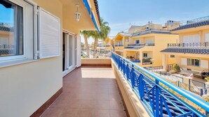 A balcony with a blue railing, a tiled floor, and a view of adjacent buildings.