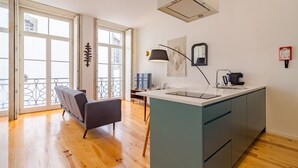 A modern kitchen with a central island, a dining area with a bench, and large windows with a balcony. - Twin Studio with Balcony view Clérigos Tower (Oporto)
