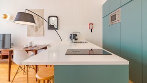 A modern kitchen with a white countertop, a black lamp, a microwave, and a small island with stools. - Twin Studio with Balcony view Clérigos Tower (Oporto)