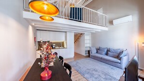 Een modern interieur met een eethoek, keuken en woongedeelte, met een trap naar een hoger gelegen verdieping.
