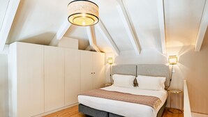Een slaapkamer met een bed, een kledingkast, een plafondlamp en een nachtkastje.