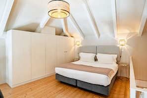 A bedroom with a bed, a wardrobe, a ceiling light, and a bedside table.